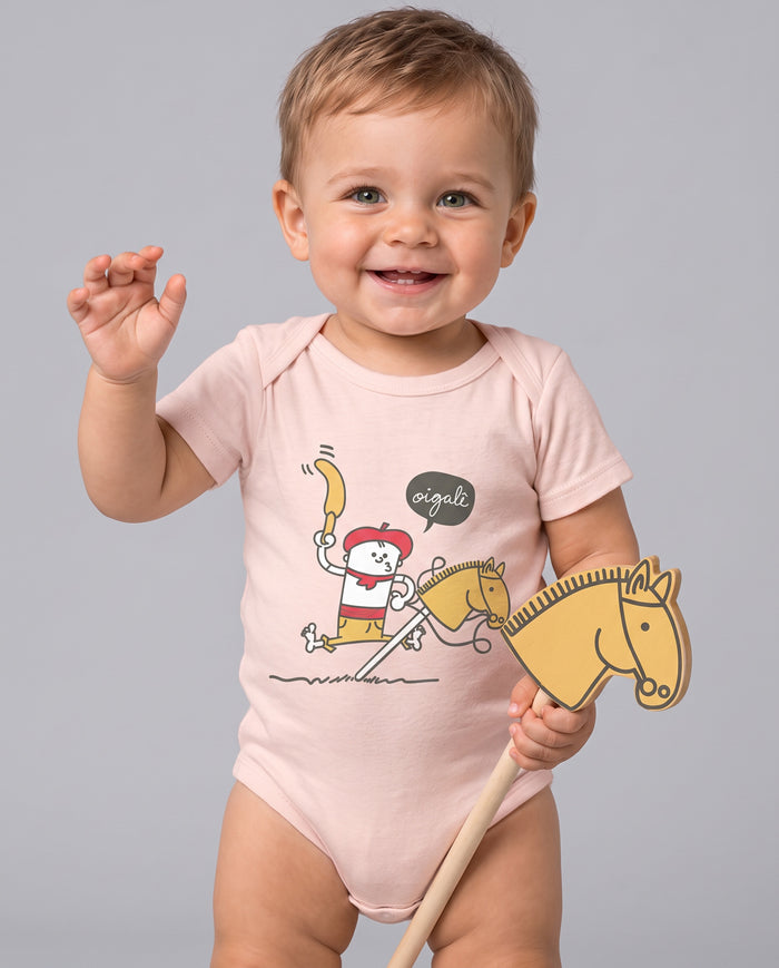 Bebê sorrindo com o Body Cavalinho de Pau na cor rosa bebê, segurando um cavalinho de pau de madeira igual ao da estampa