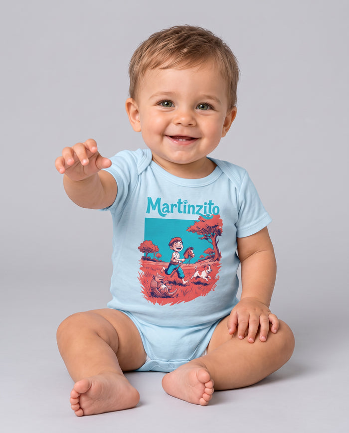 Bebê sentado e sorrindo com o Body Martinzito do Rincão na cor azul bebê, com a estampa do guri no cavalinho de pau, o cachorro e o tatu