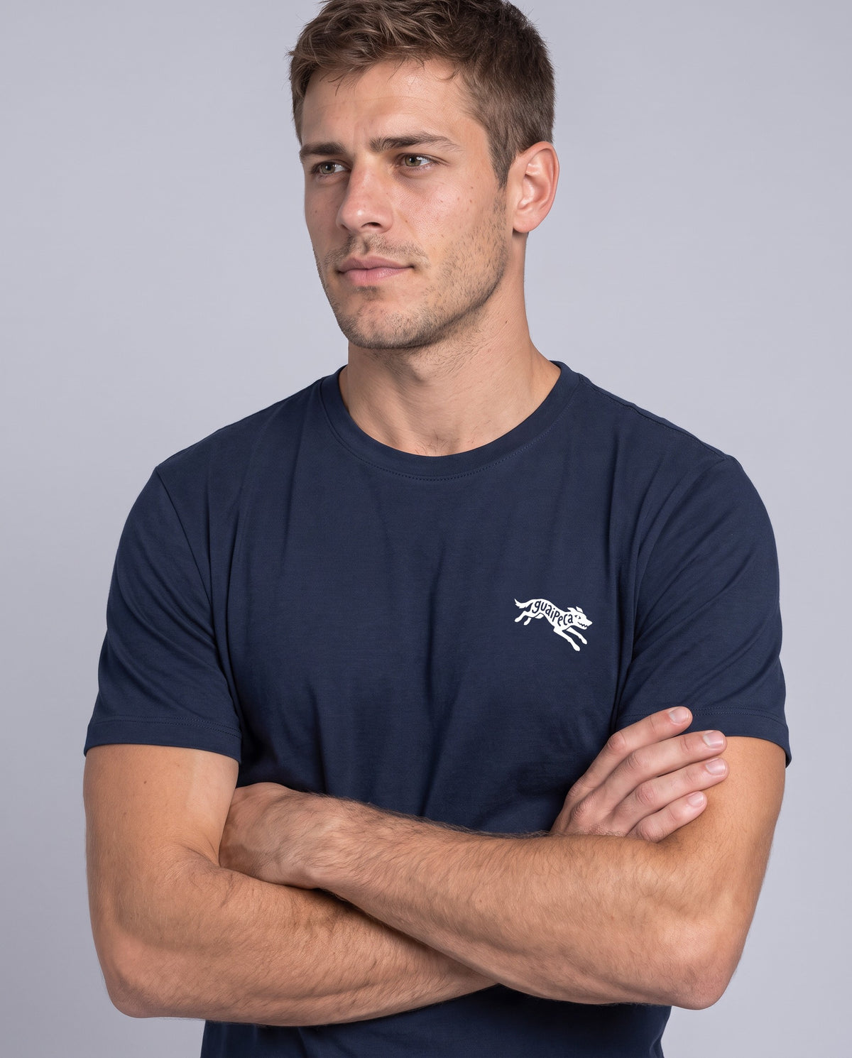 Homem de braços cruzados vestindo a Camiseta Guaipeca da Série Sem Alarde, modelagem masculina, na cor marinho