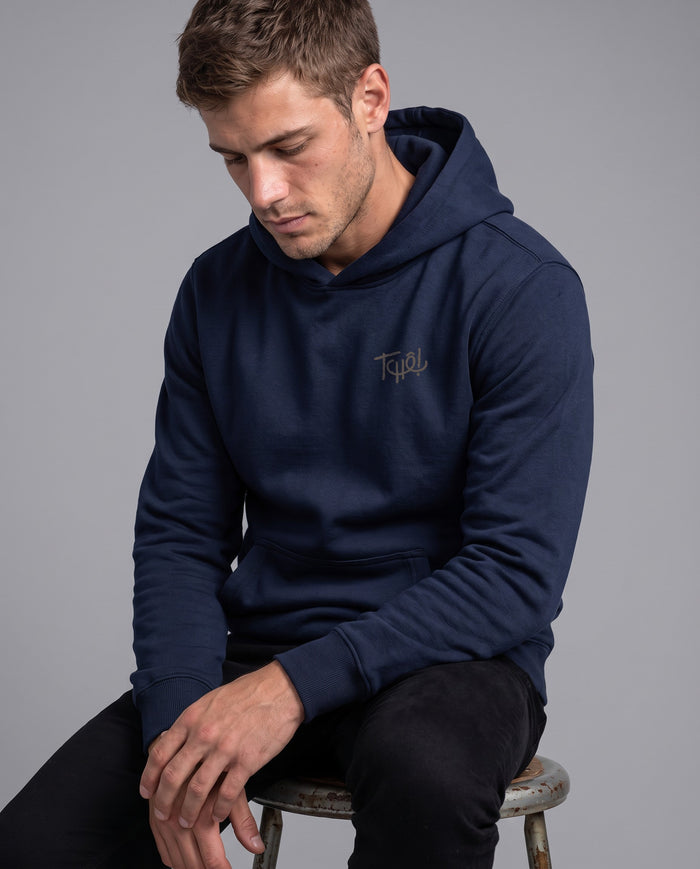 Homem sentado num banco vestindo o Hoodie Tchê Sem Alarde na cor marinho