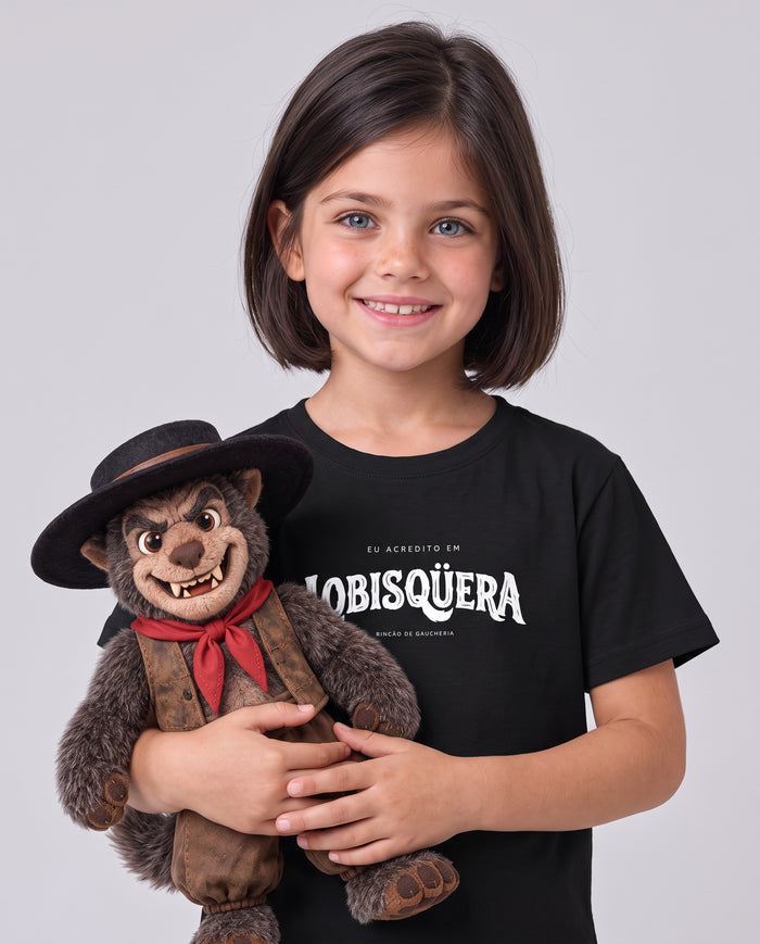Menina sorrindo e abraçando um boneco do lobisomem de chapéu e lenço vermelho, vestindo a Camiseta Eu Acredito em Lobisqüera infantil na cor preta