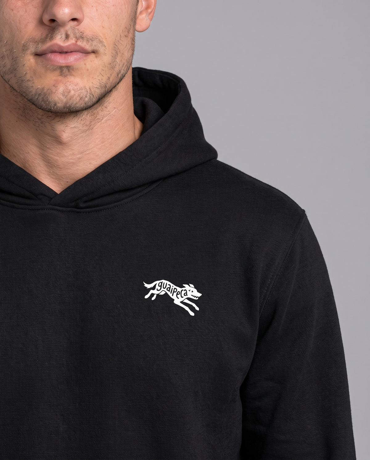 Homem vestindo o Hoodie Guaipeca da Série Sem Alarde na cor preta, com a estampa pequena no peito