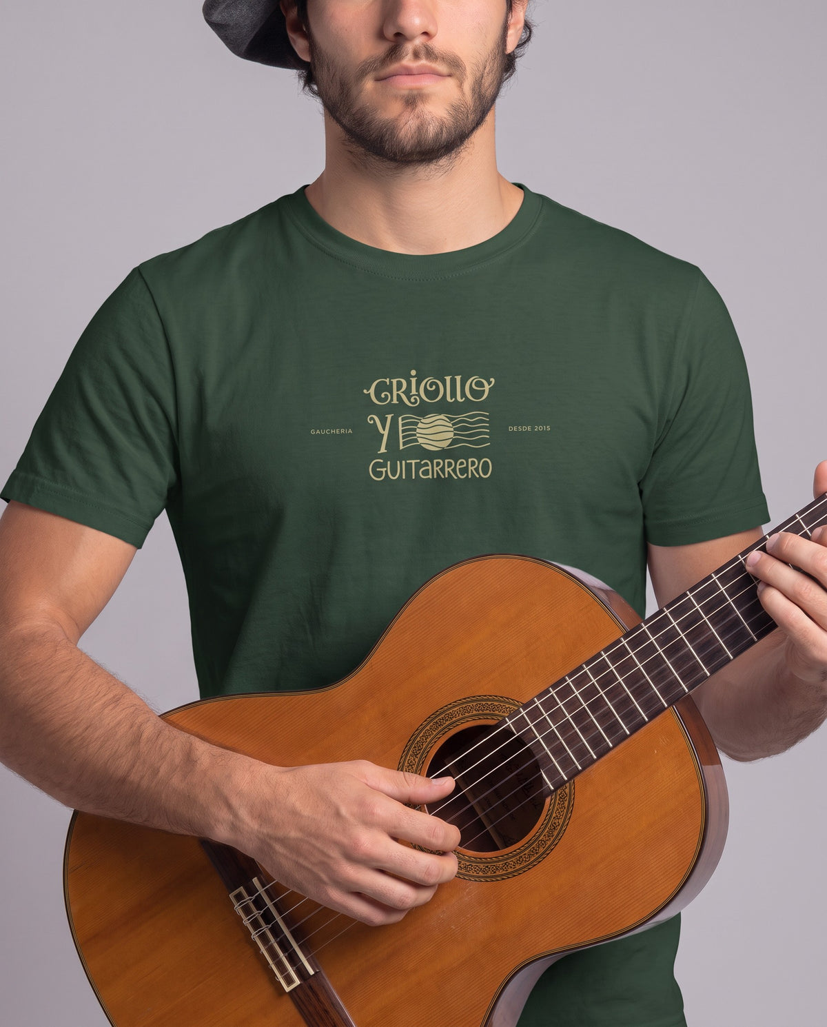 Homem tocando violão vestindo a camiseta Criollo y Guitarrero na cor verde, com a estampa dourada no peito