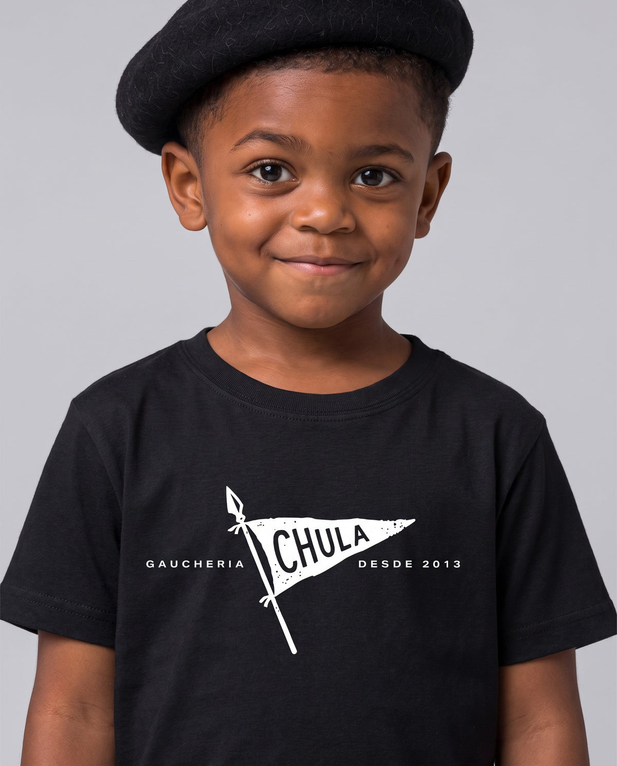 Menino de boina sorrindo, vestindo a camiseta infantil Chula Gaúcha na cor preta