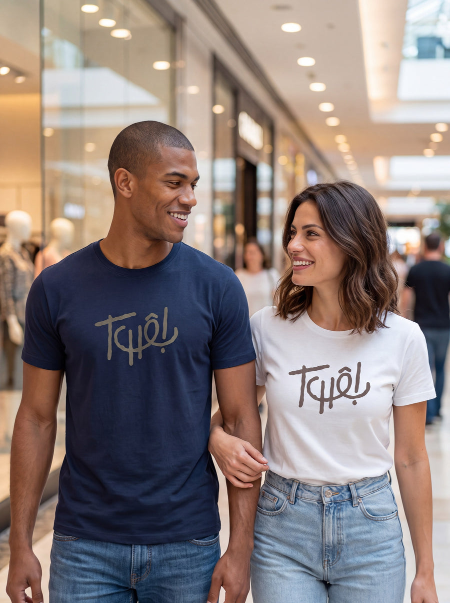 Casal de braços dados passeando num centro de compras, os dois com a camiseta Tchê!, ele de azul marinho e ela de branco